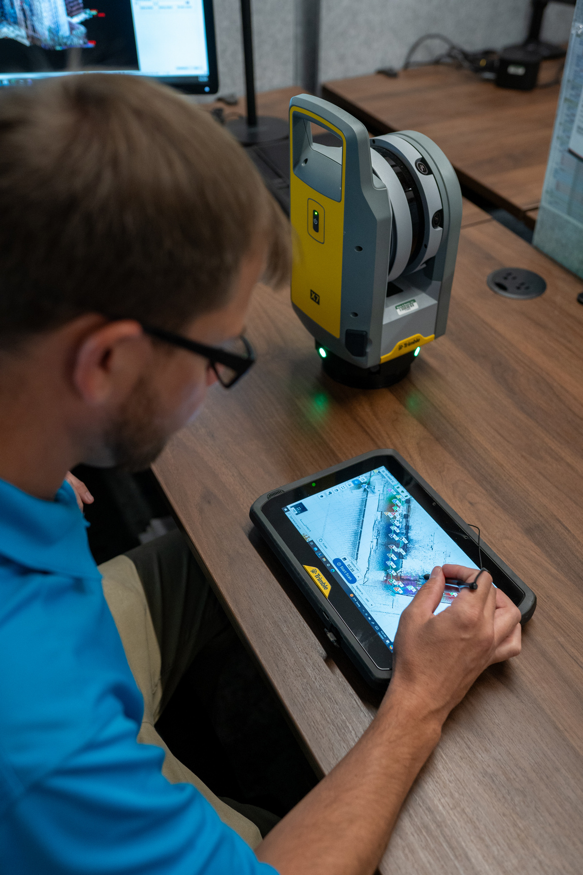 Bayer Becker Scanning Man using a touchscreen tablet at a desk with electronic equipment.