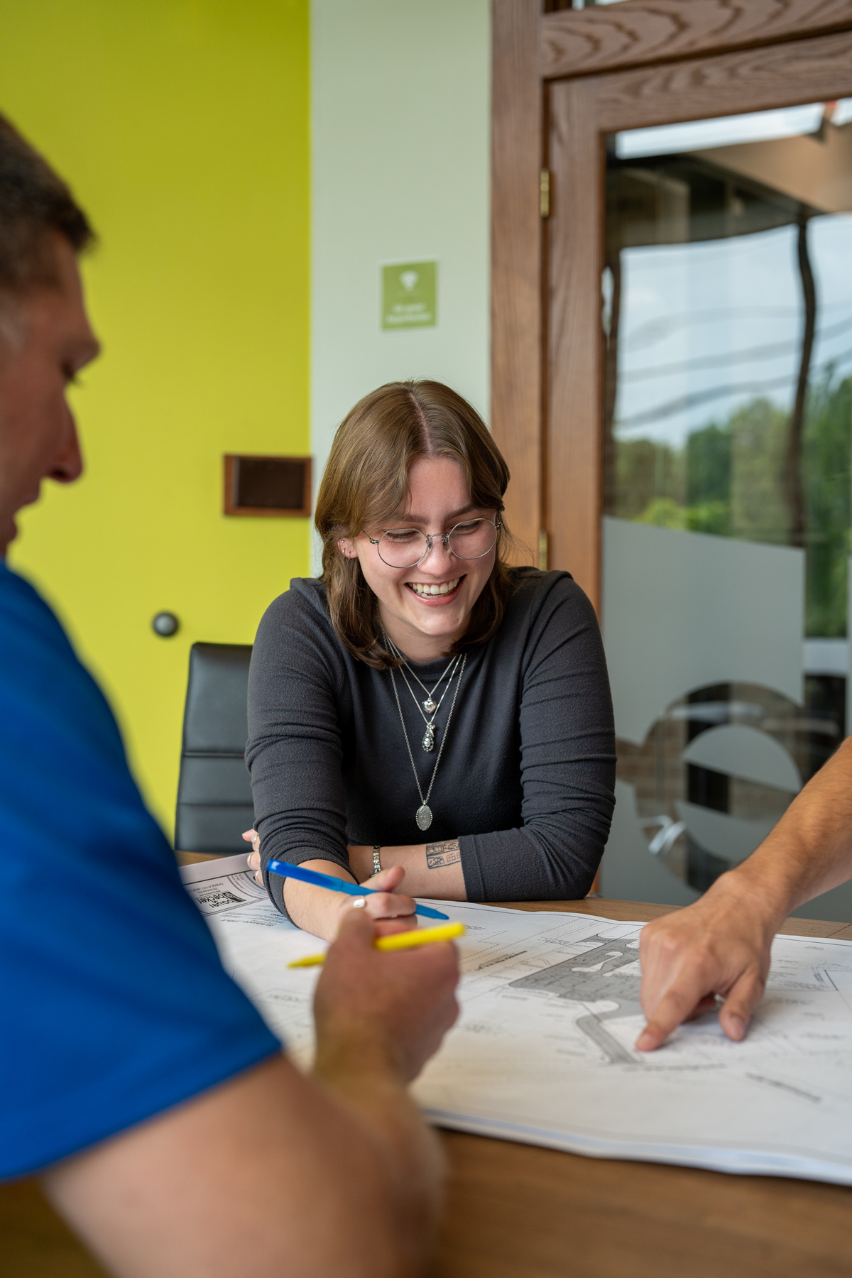 Bayer Becker Comprehensive Team Group discusses plans at table, woman smiling.
