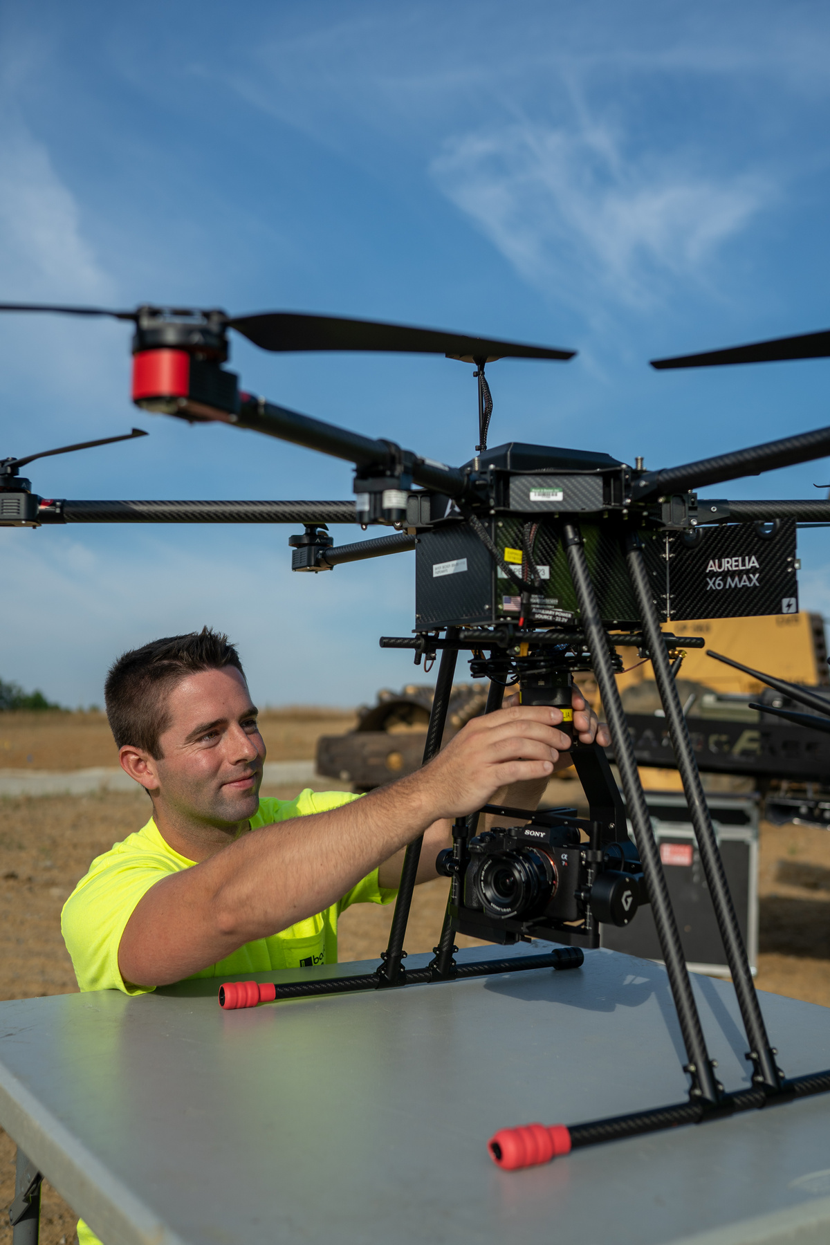 Bayer Becker Land Surveying Man adjusting large drone outdoors on a sunny day.