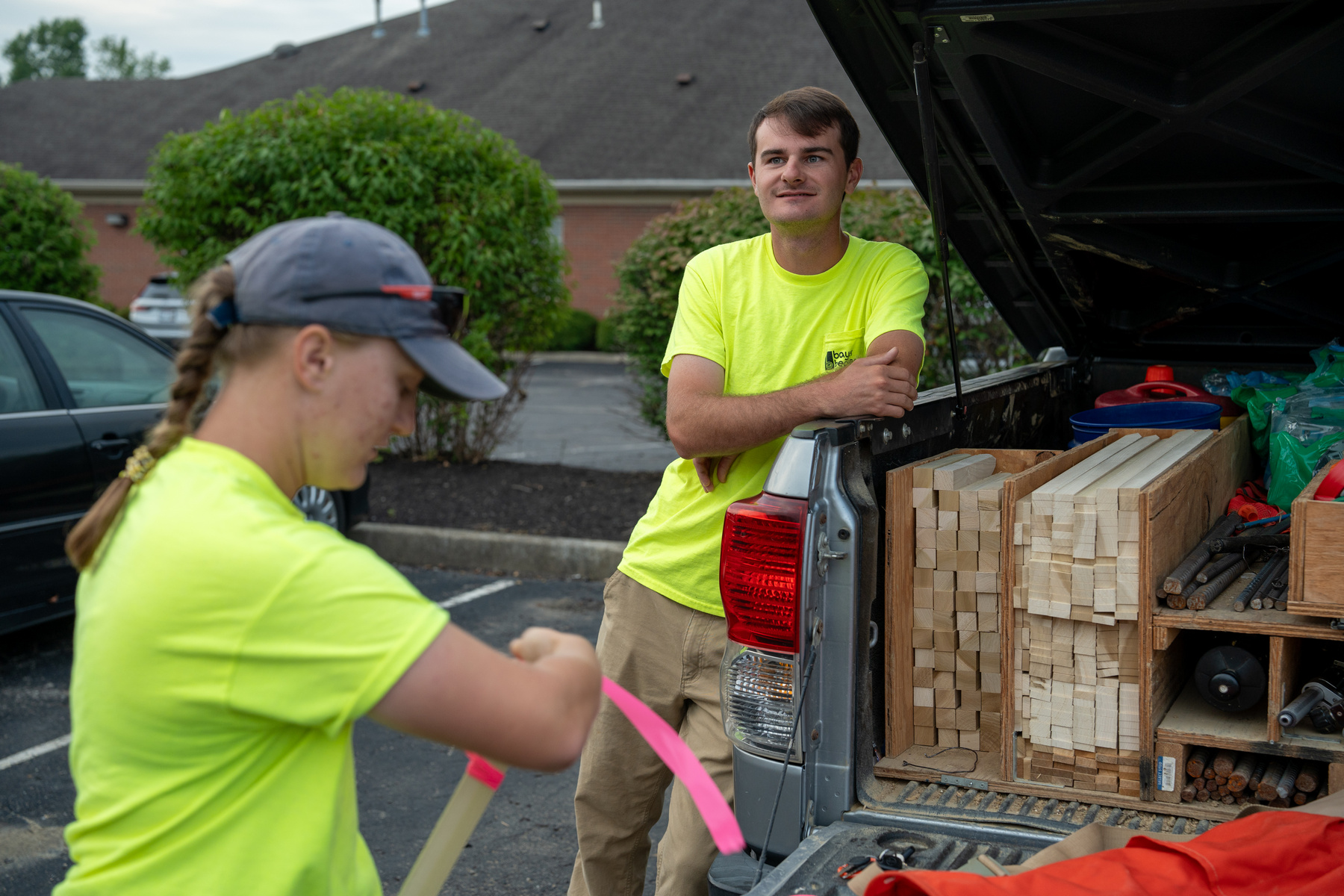 Bayer Becker Is Down To Earth Two workers in yellow shirts near a truck full of construction materials.