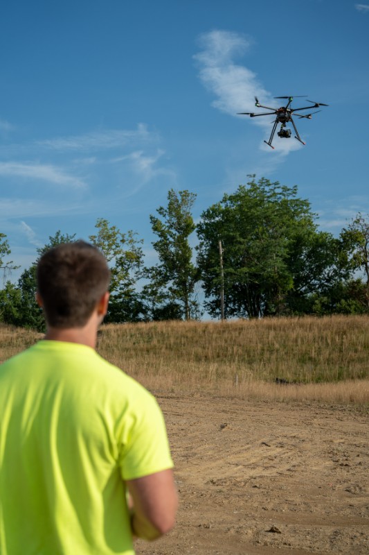 Bayer Becker sUAS Surveying Man in yellow shirt flying a drone outdoors.