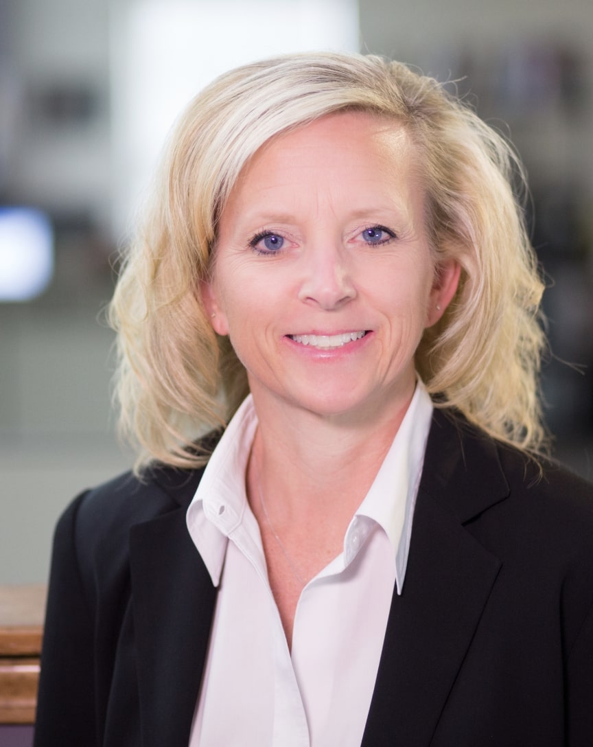 Etta Reed - Bayer Becker Smiling woman in a black suit jacket in an office setting.