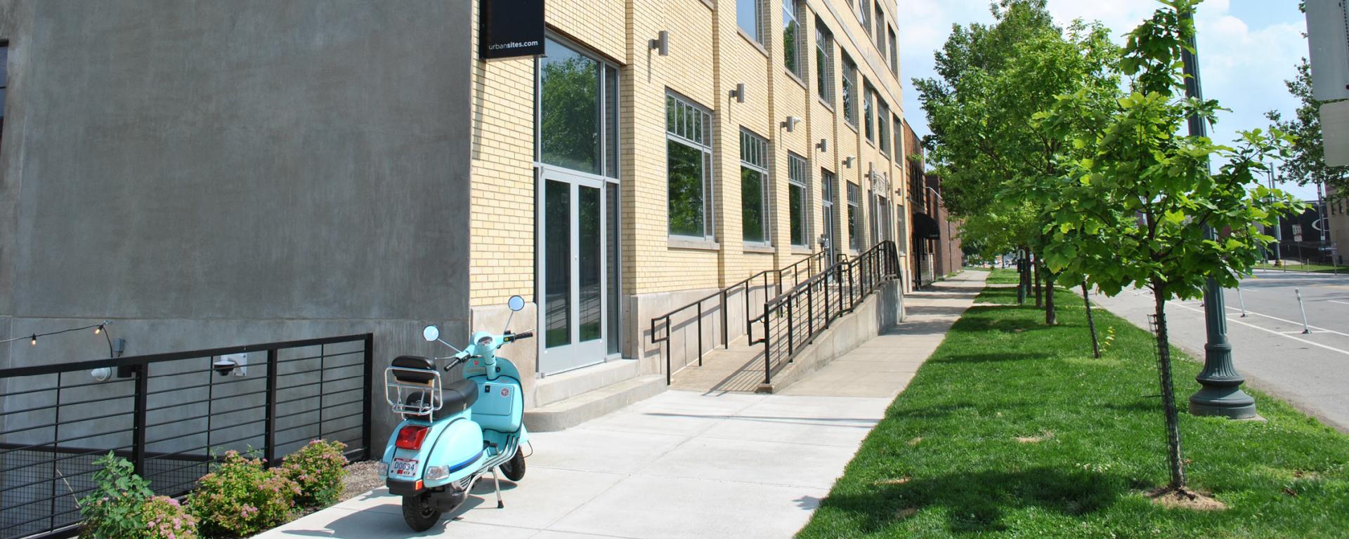 light blue scooter parked next to yellow brick building