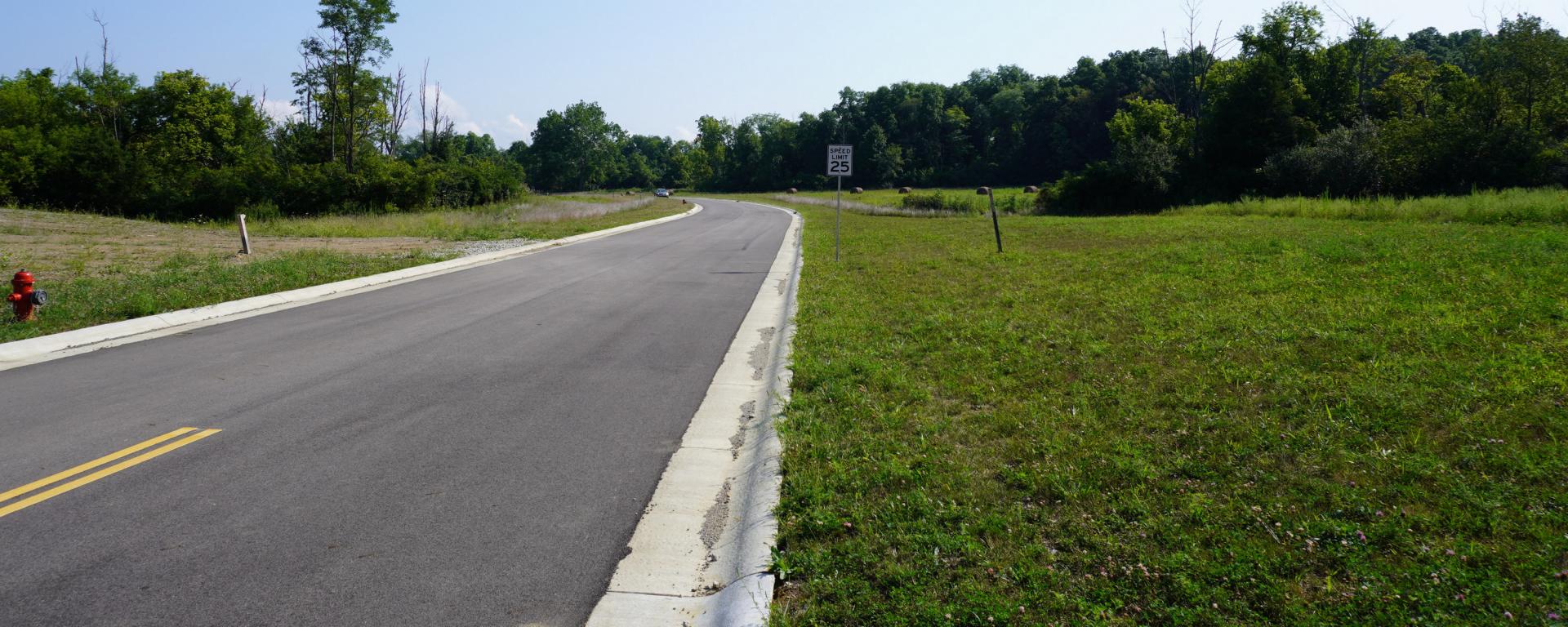 newly paved roadway surrounded by grass