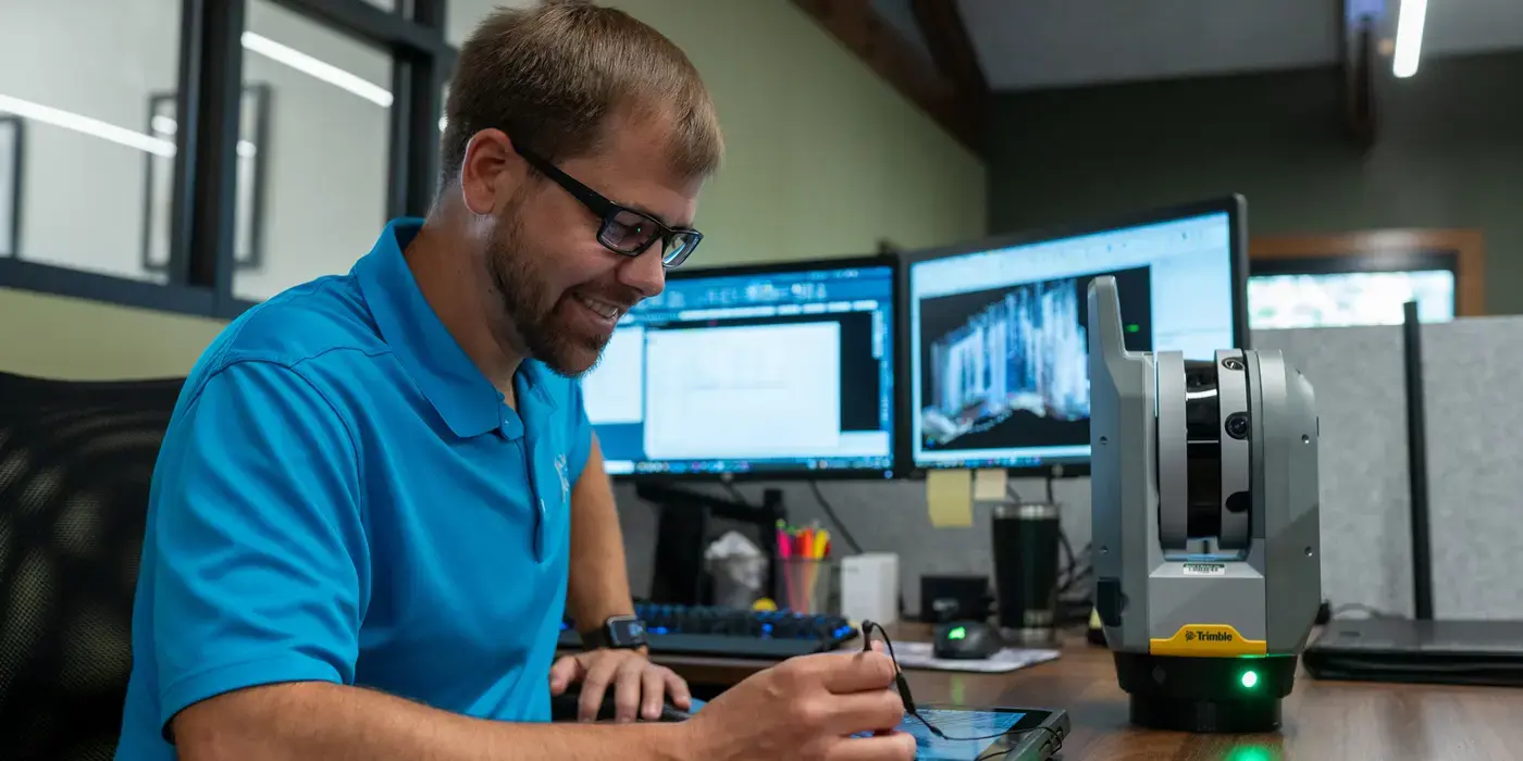 Bayer Becker Career Opportunities Man in a blue shirt works at a desk with dual monitors.