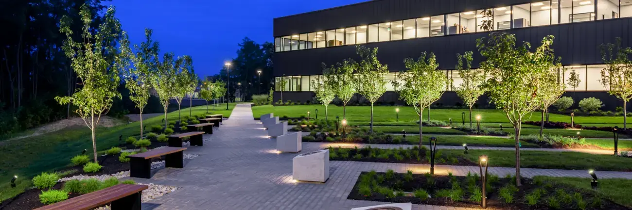 DAV Memorial Garden - Erlanger, KY Walkway and garden beside a lit modern building at dusk.