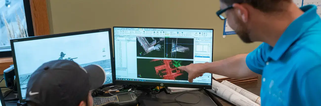 Bayer Becker Geovisualization Two men working at a desk with dual computer monitors.